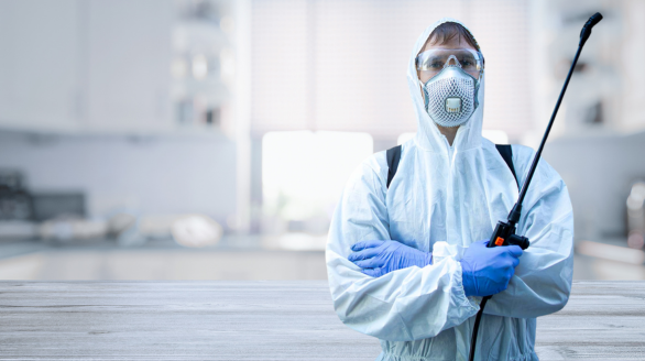 A professional soft services team in protective gear is preparing for pest control in a bright, modern indoor setting.