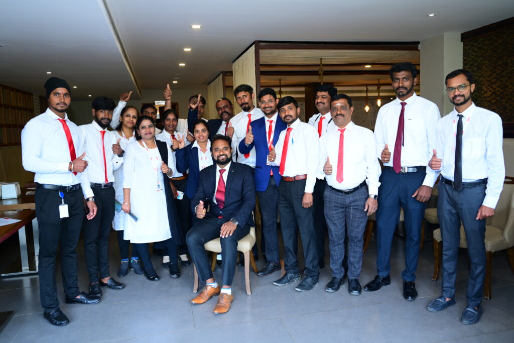 A team of professionals in white shirts and red ties pose together, representing Best Facility Management Services in Bangalore