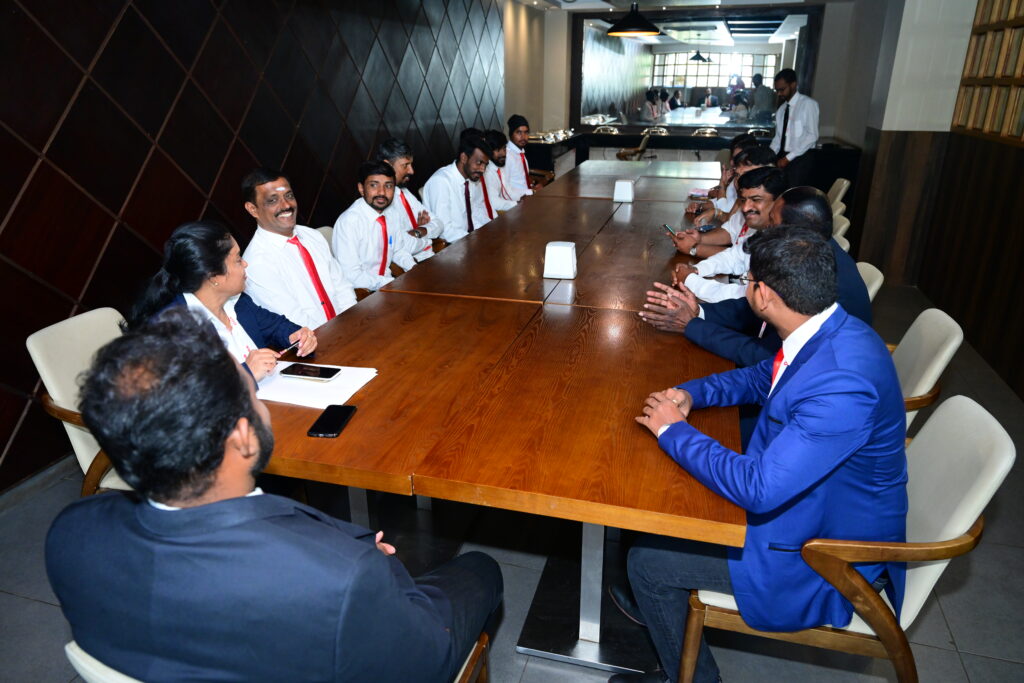 A professional team in business attire attends a meeting around a large wooden table, representing Administrative Services in Bangalore