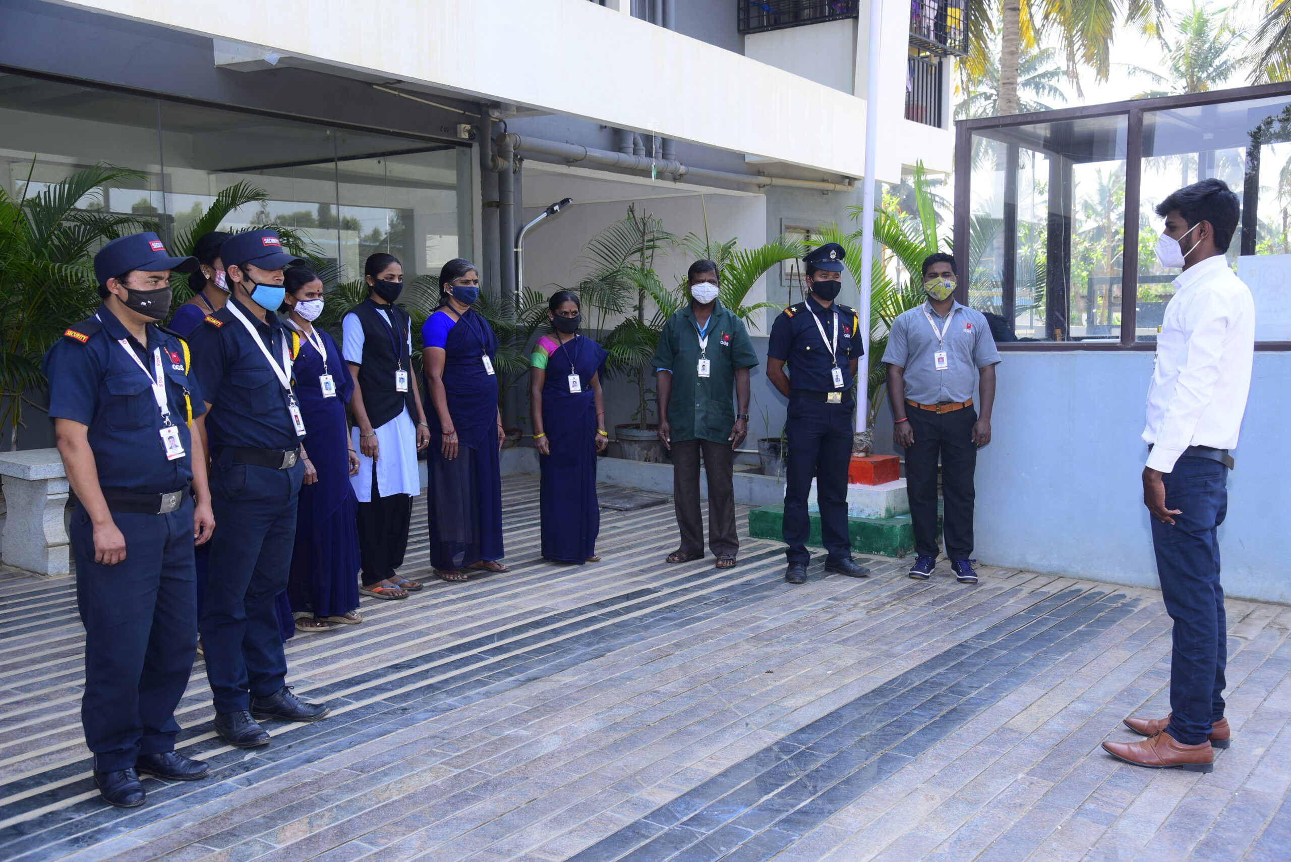 A security team stands in uniform while receiving instructions outside a building, representing Security Services in Bangalore.